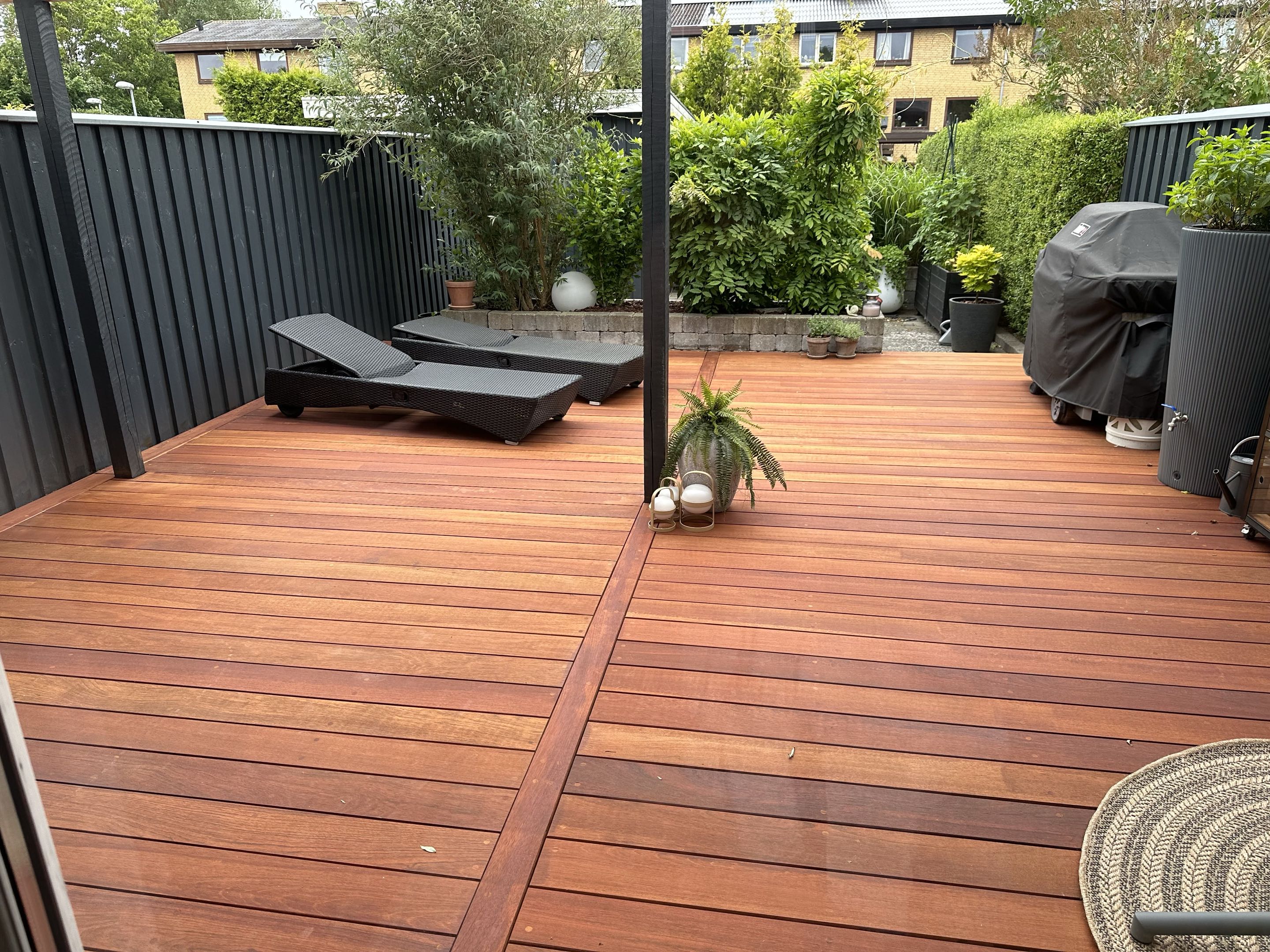 Terrasse i hårdttræ med rammebrædder og sort plankeværk